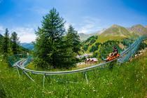 Verdon Express rail toboggan, two-seater gondola, series of hairpin bends in a verdant setting, unobstructed view of the surrounding mountains