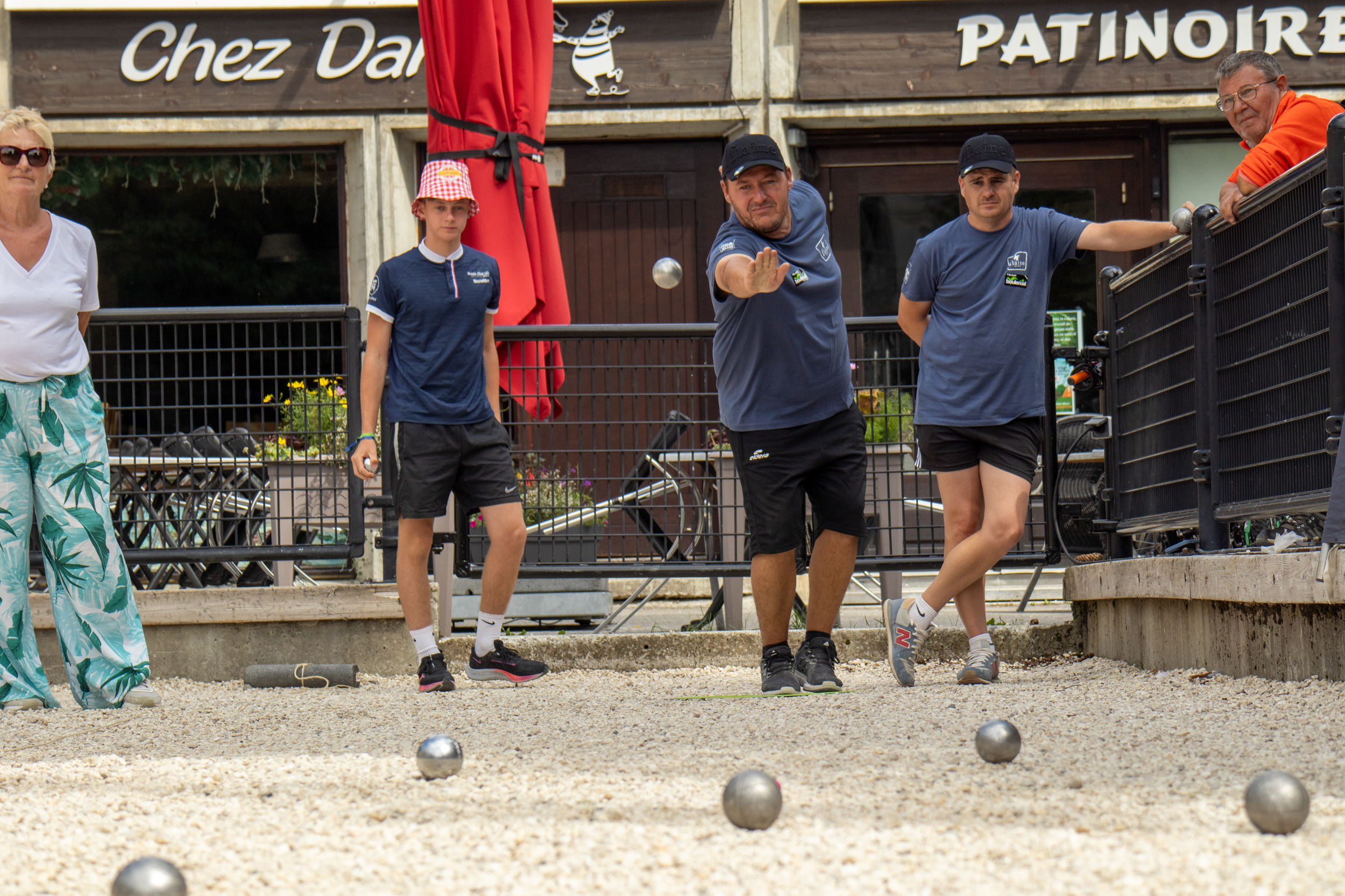 A focused thrower and his team take part in a pétanque tournament
