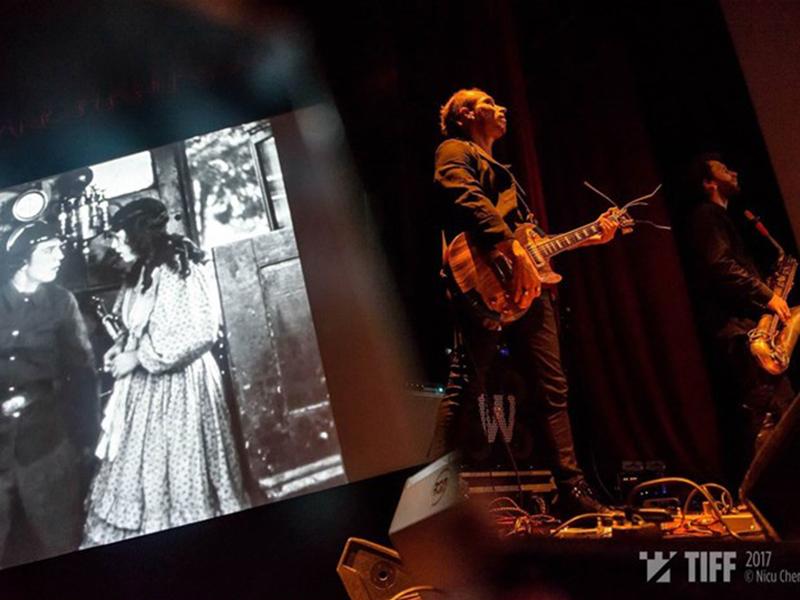 Musicien jouant de la guitage devant un écran de cinéma