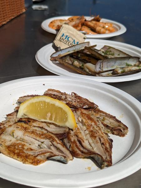 Une assiette de filets de Sardines grillés, une de couteaux, une de crevettes.