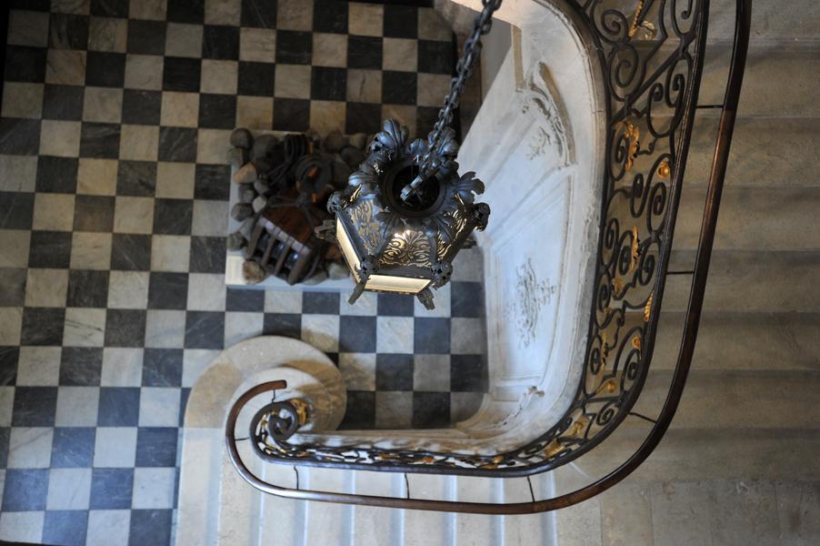 Escalier monumental du musée du Nouveau Monde à La Rochelle, vu du dessus, avec sa rampe en fer forgé et son sol en damier noir et blanc.