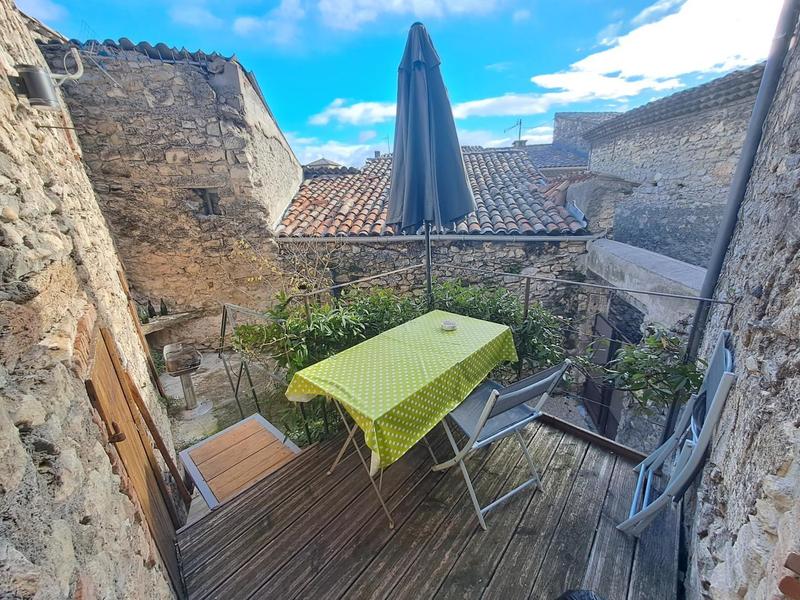 Terrasse avec salon de jardin et parasol et son accès cour privative fermée. 