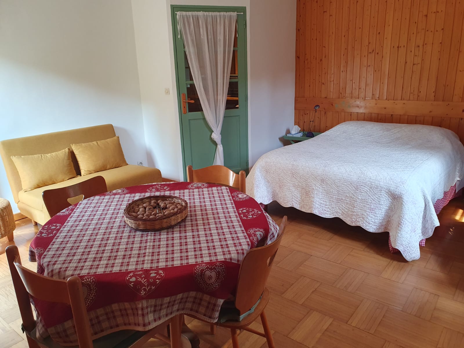 Coin nuit chaleureux du gîte de Carpat avec lit double, mobilier en bois et petit espace repas convivial.