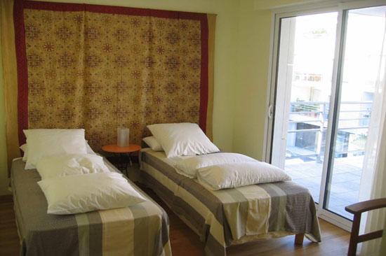 Chambre avec deux lits simples, donnant sur le balcon.