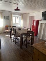 Séjour lumineux avec table à manger, frigidaire, fenêtres, ameublement bois