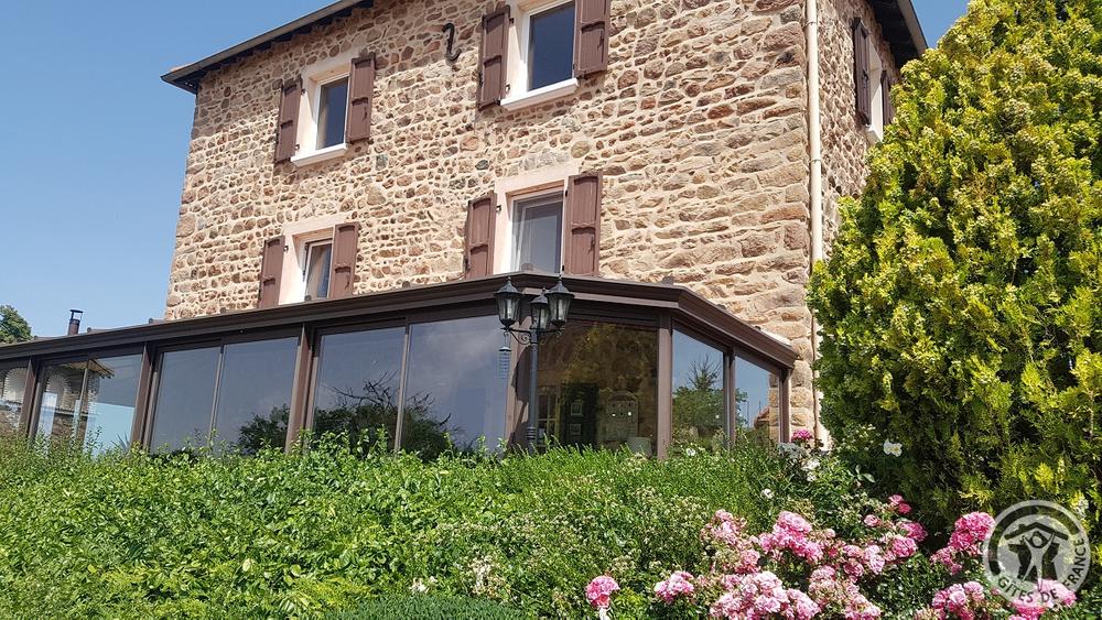 Chambres d\'hôtes \'La Ferme Fleurie\' à Thizy-Les-Bourgs, en Haut Beaujolais, dans le Rhône, proximité Roanne (42) et Lac des Sapins : la maison principale et véranda.