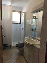 Salle de bains lumineuse avec bac à douche, grand évier, miroir, ameublement bois, fenêtre