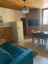 Coin séjour avec canapé, table à manger, TV murale, fenêtre