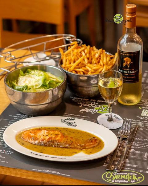 Escalope de saumon servi avec frites, salades et vin blanc.