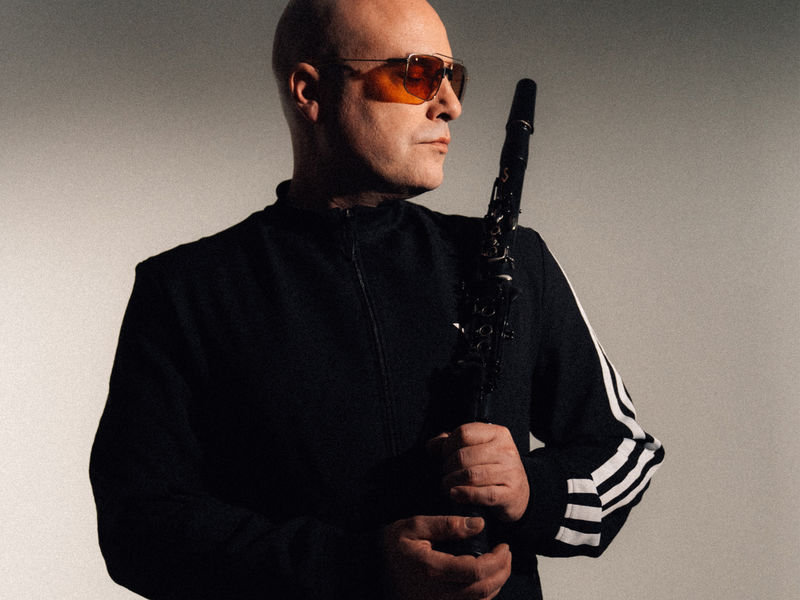Homme à lunette en costume sombre maniant son instrument