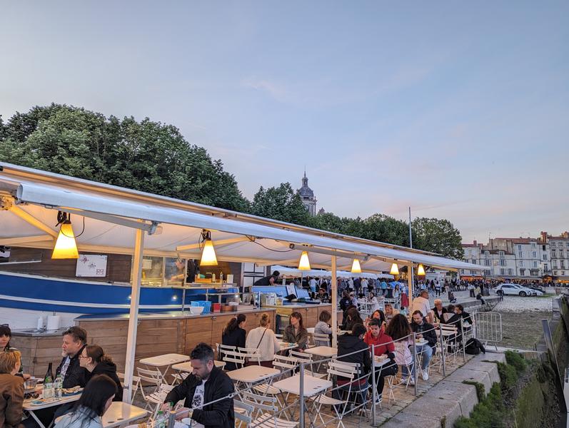 La terrasse bondée au couché du soleil, avec des lampions allumés.