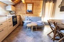 Séjour lumineux avec coin cuisine, TV, table à manger, canapé, ameublement bois, carrelage au sol, porte-fenêtre