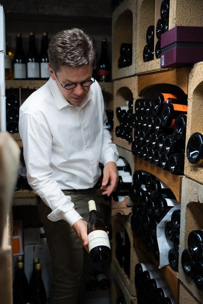 Le propiétaire présentant une bouteille de vin rouge dans la cave
