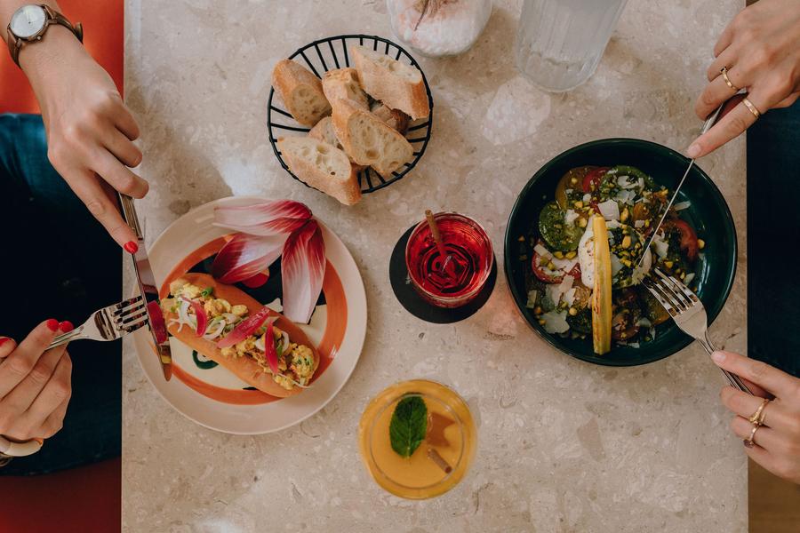 Deux personnes dégustant un hot-dog et une salade composée.