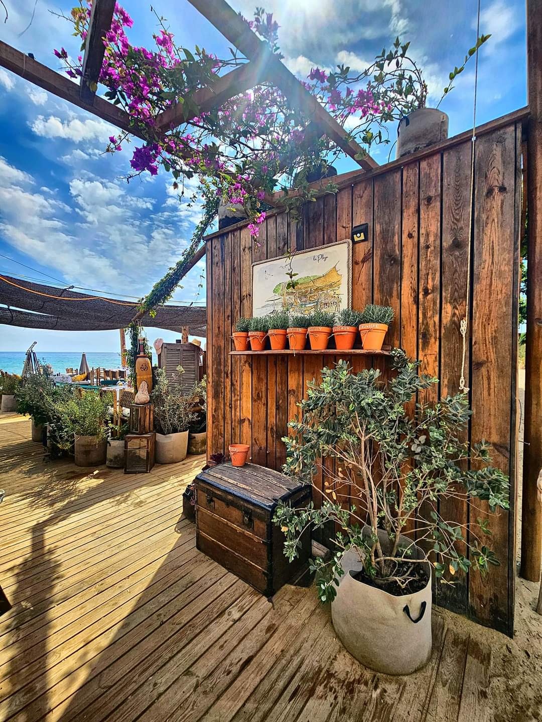 Entrée en bois et végétation du restaurant La Plage