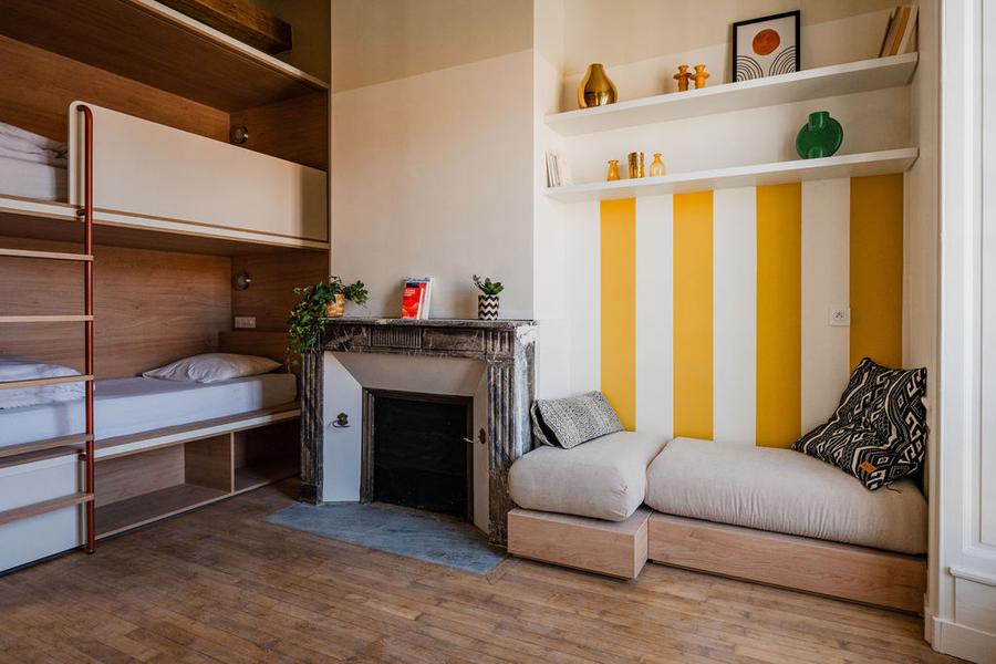Un dortoir avec deux lits superposés, une cheminée et une banquette dans un coin.