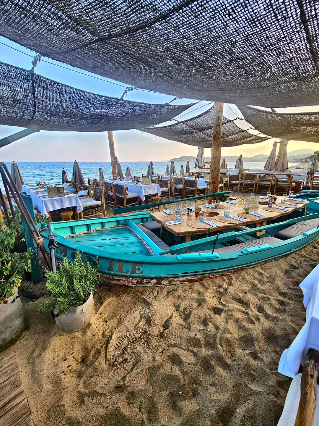 Le restaurant La Plage, sa barque turquoise et sa terrasse sur le sable face à la mer