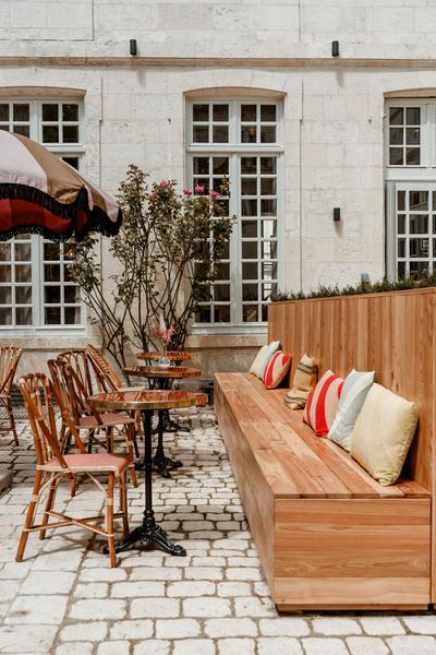 Une rangée de tables avec des chaises et ne longue banquette sur la terrasse.