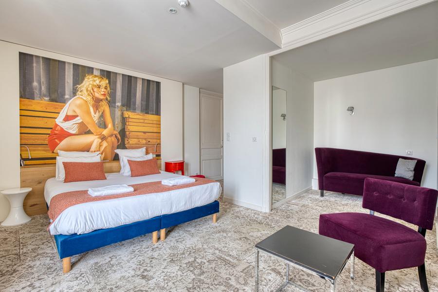 Une chambre "Deluxe" avec un lit double, un canapé, un fauteuil et une table basse.