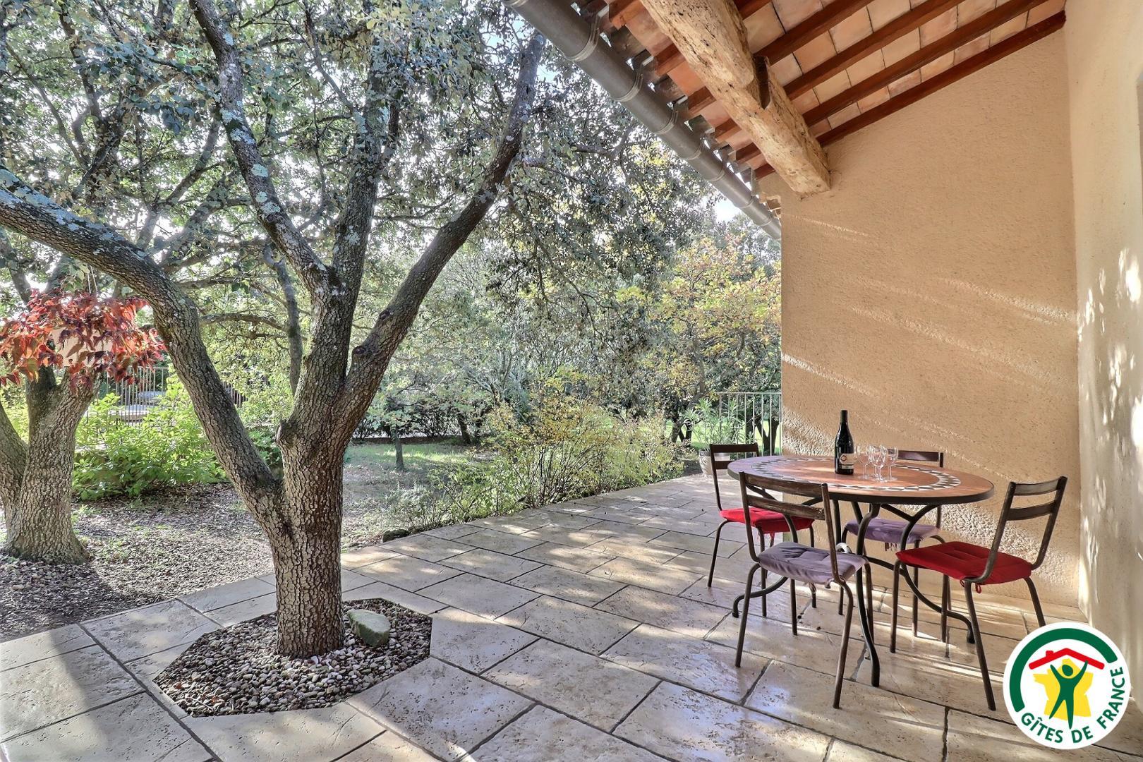 La terrasse du gîte, vue sur le parc arboré et la piscine