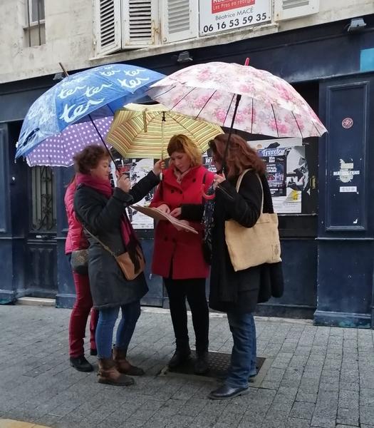 Un groupe de femmes avec des parapluie, à lire le carnet de bord.