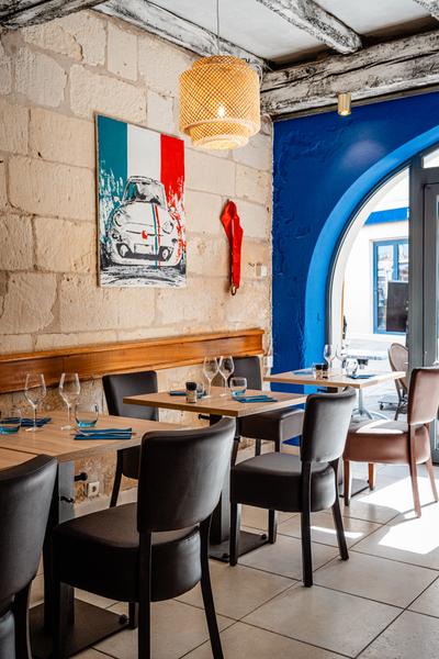 La salle du restaurant avec des tables, des chaises et des banquettes.