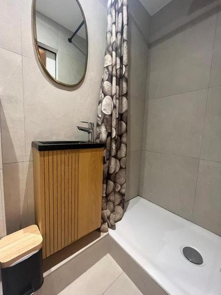 Un bac de douche avec rideau, un lavabo. avec miroir.