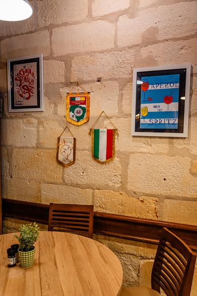 Un coin du restaurant avec une table ronde et deux chaises, des cadres et autres décorations accrochées au mur.