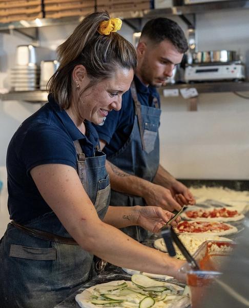 Sabrina et un autre employé font les pizzas