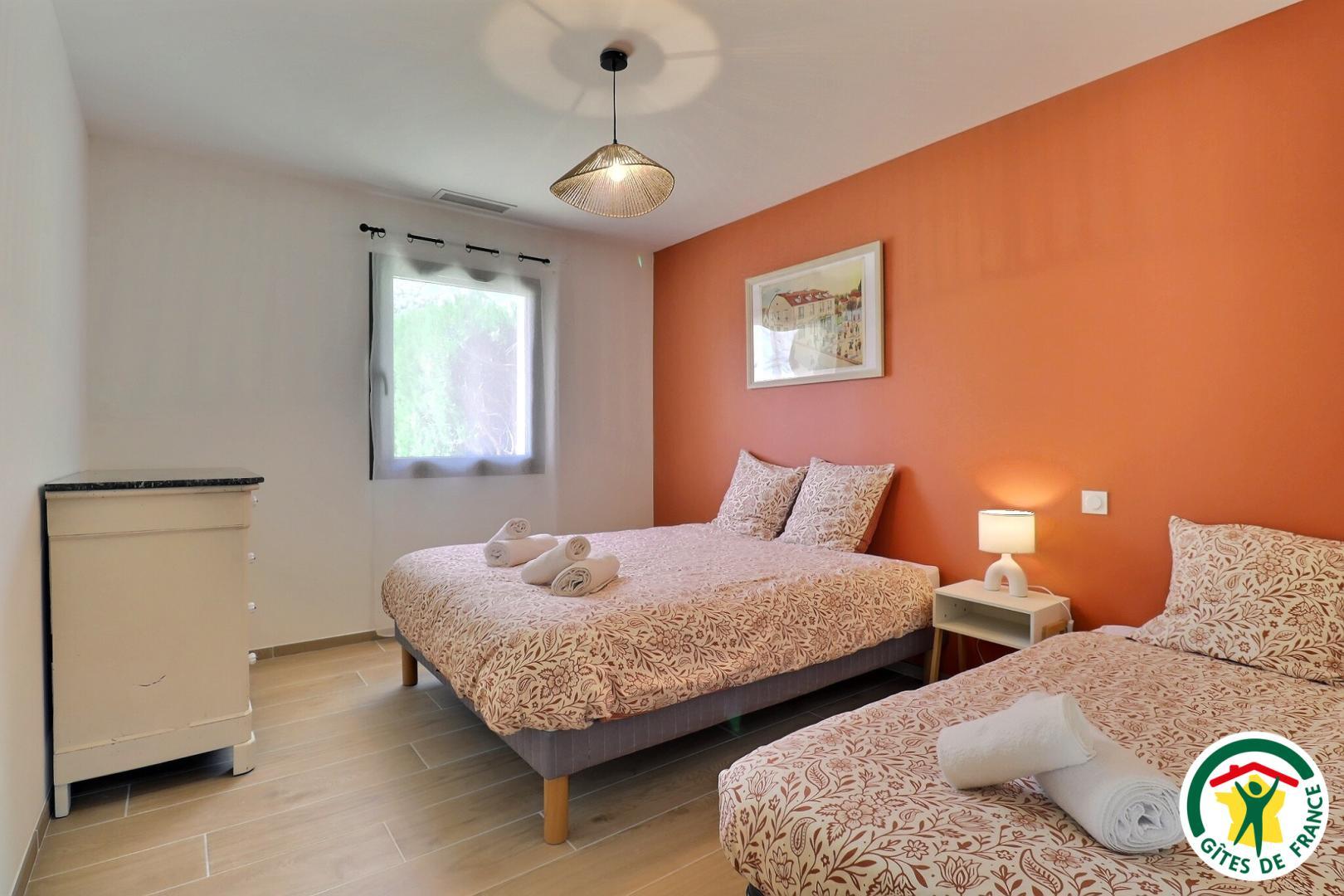 La chambre avec un lit double et un lit simple (1x160x200 + 1x90x190), commode, climatisation, volet roulant électrique à la fenêtre.