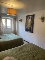 Chambre à coucher lumineuse avec deux lits simples, ameublement bois, fenêtre