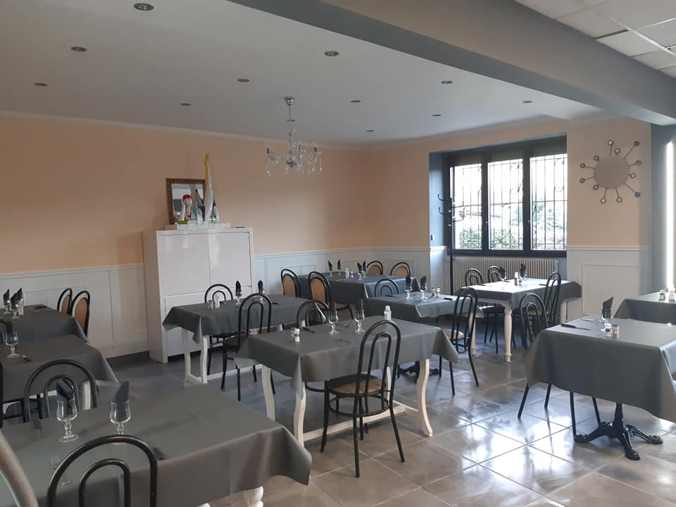 Salle du restaurant avec plusieurs tables couvertes de nappes grisses.