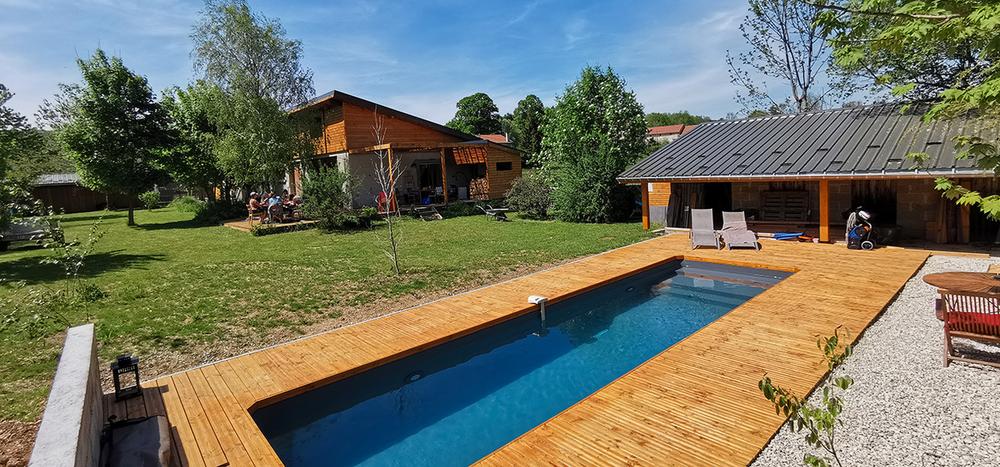 Couloir de nage dans un jardin arboré. En arrière plan les gîtes et la maison du propriètaire