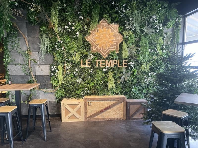 L'entrée du bar avec la grande pancarte en faux feuillage "Le Temple"