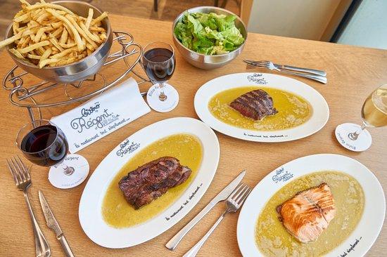 Deux plats de viande et un plat de poisson, accompagné de frites, de salade et de verres de vin.