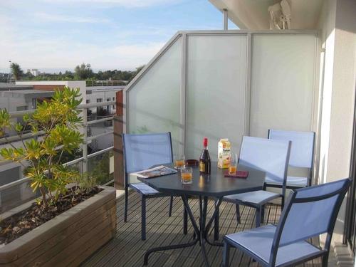 Une table avec des verres et du jus d'orange, et ses chaises sur le balcon.