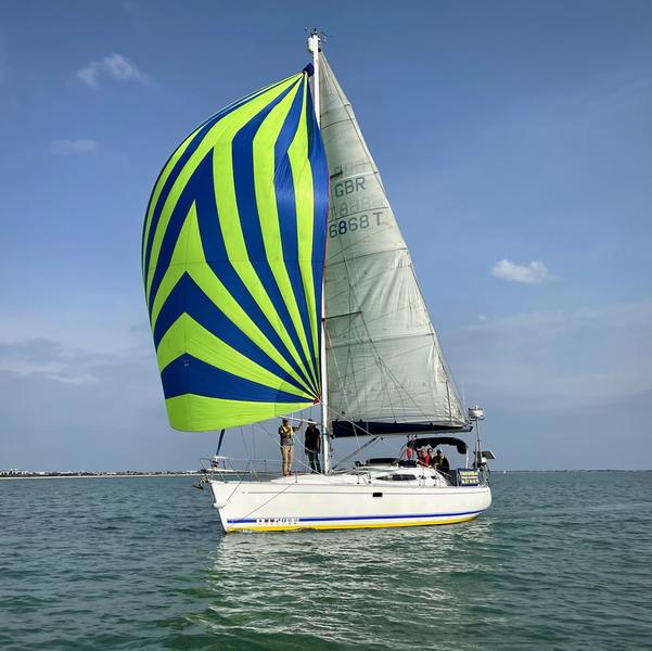 Un voilier avec la boile bleue et verte, en mer.