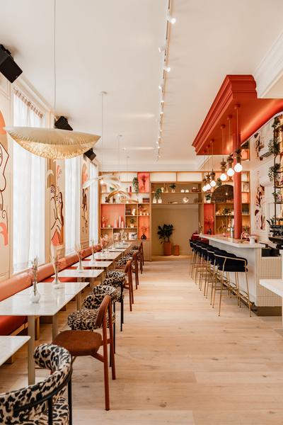 La salle du restaurant, avec des tables, des chaises et une grande banquette le long du mur.
