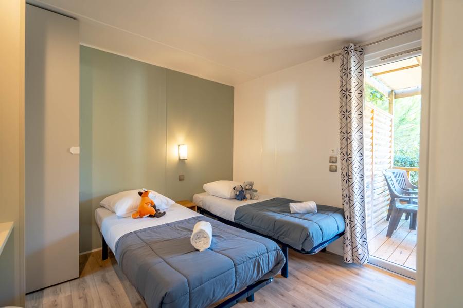 Une chambre avec deux lits simples, des peluches sont sur chacun des lits.