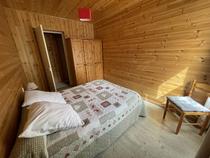 Chambre à coucher lumineuse avec lit double avec ameublement bois, lambris, fenêtre