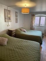 Chambre à coucher lumineuse avec deux lits simples, ameublement bois, fenêtre