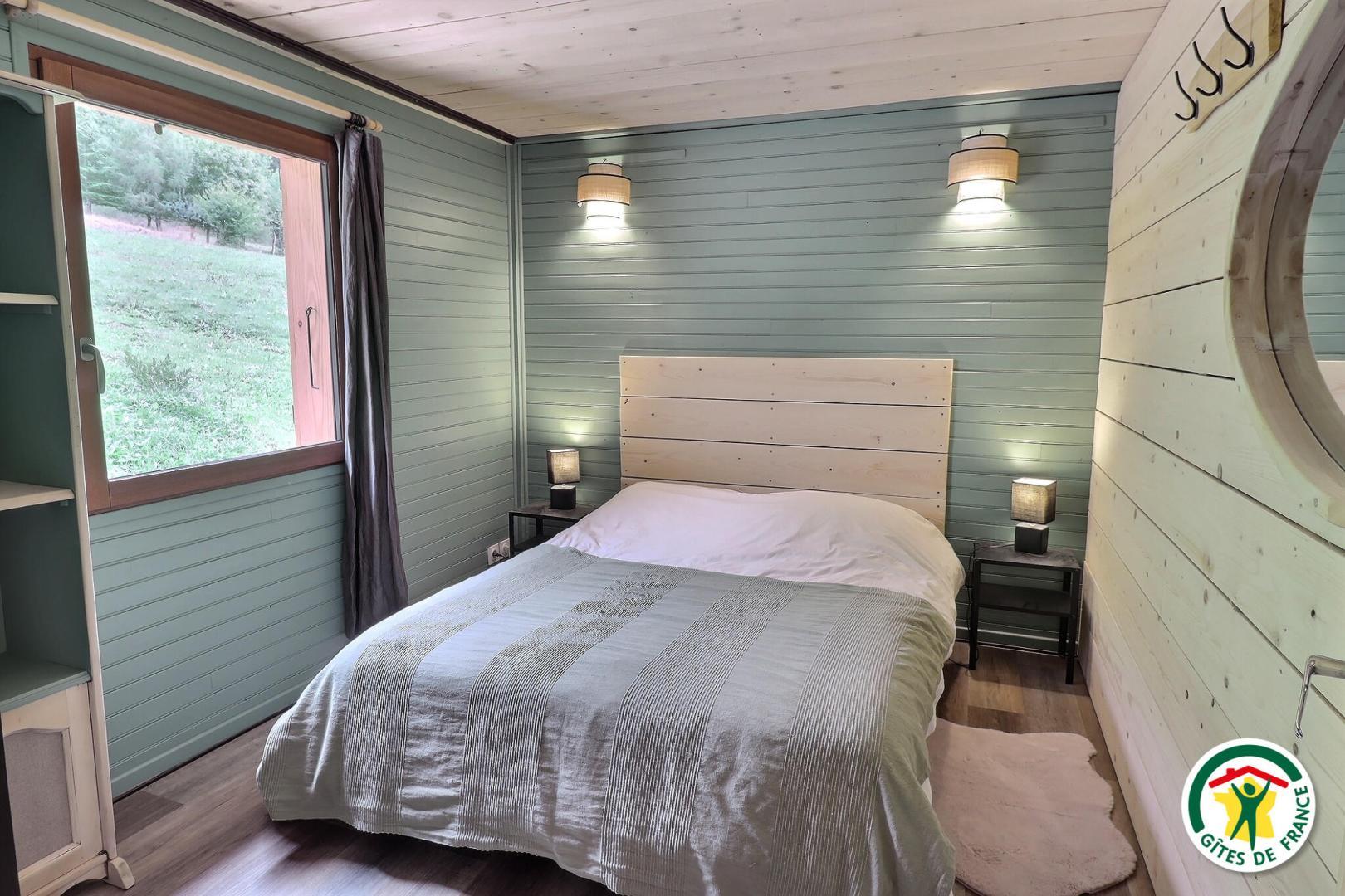 La chambre du rez-de-chaussée : lit 160x200cm, fenêtre avec volet et rideaux, armoire avec étagères