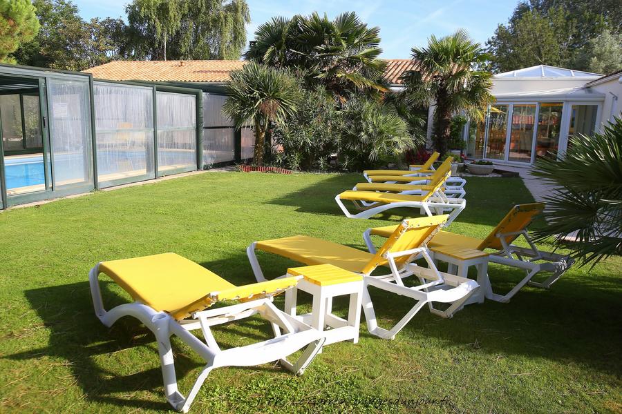 Jardin avec transats et vue sur la piscine couverte et la maison