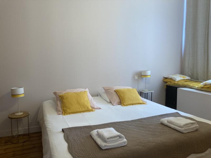 Chambre avec un lit double, un coussin de sol sur le rebord de la fenêtre.
