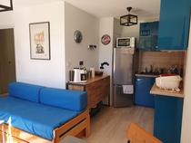 Espace séjour avec canapé-lit et table basse, espace cuisine tout équipé