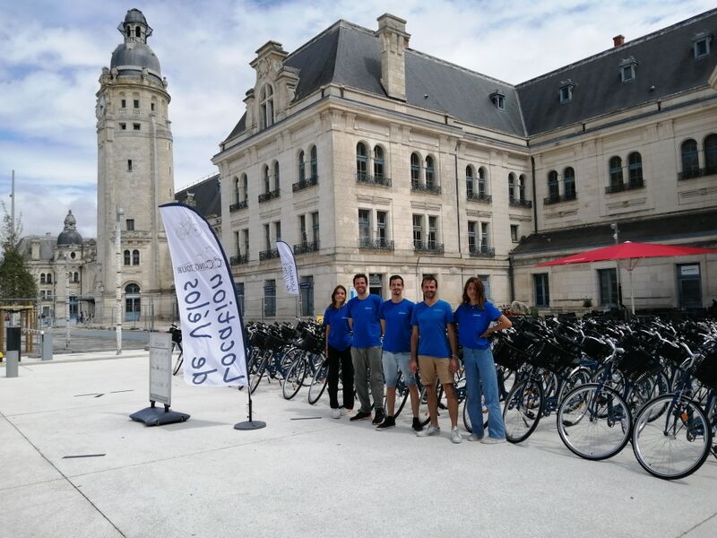 L'équipe de Cycling Tour posant devant les vélos, sur le parvis de la gare