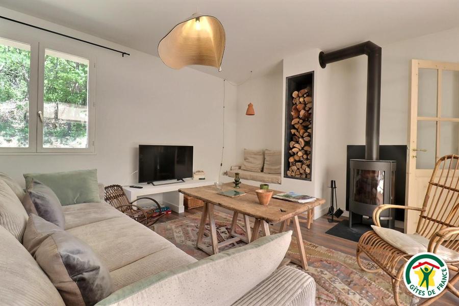 Le salon, avec un grand canapé, une banquette et un fauteuil en rotin années 60 chiné