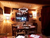 Salle intérieure du restaurant, tables et chaises, ambiance lumineuse et confortable, décoration montagne