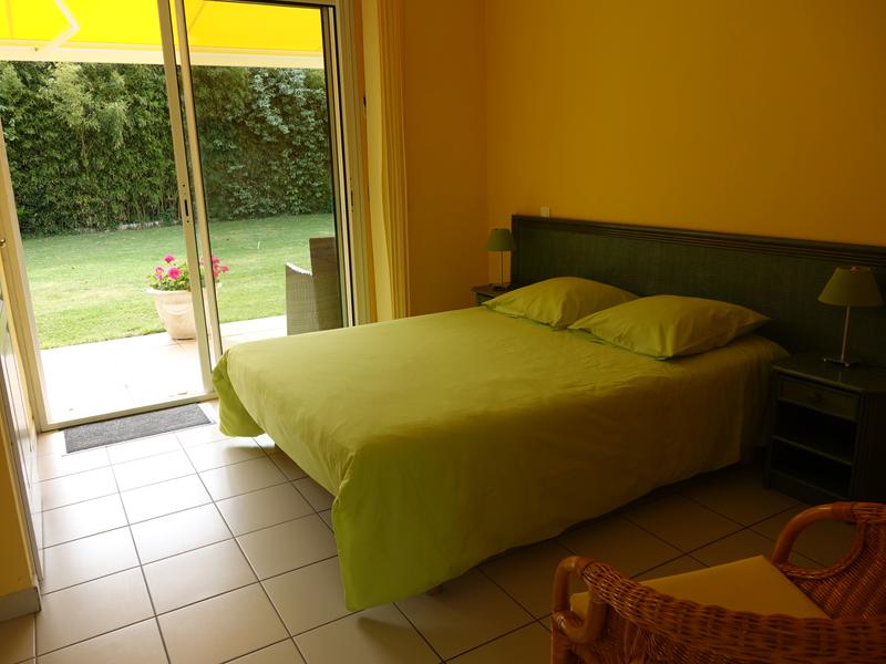 Chambre verte avec baie vitrée donnant sur le jardin