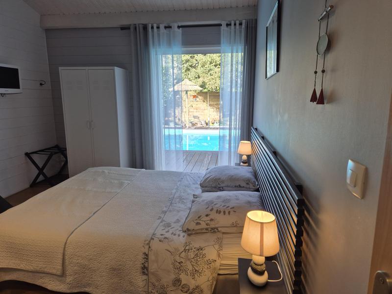 Une chambre avec lit double, donnant sur la piscine.